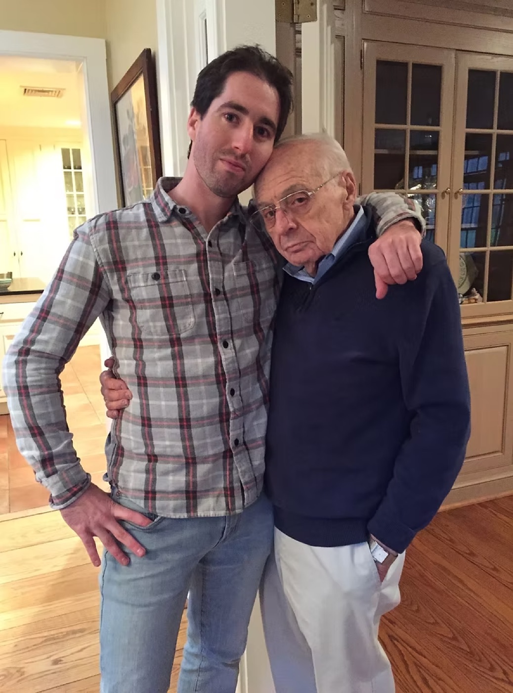 Josh Oaktree as a young man standing arm-in-arm with his grandfather Albert Boscov inside a home